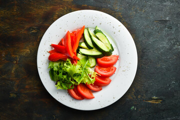 Assorted vegetables in a plate. Slicing fresh vegetables: cucumber, tomato, pepper. Restaurant menu. Top view.
