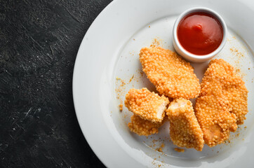 Fried chicken nuggets with ketchup sauce on a plate. Top view.