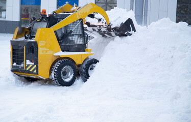 Snowfall.There is a lot of snow in the city.Snow removal by a special tractor.