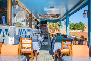 Interior of a fish restaurant open terrace decorated in a blue colour. Spacious restaurant hall is empty, there are no visitors at the tables. Terrace offers city views