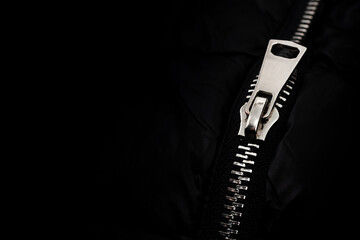 White lock with a zipper on clothes, jacket, jacket close-up on a black background. Lightning.