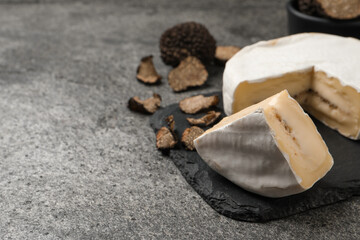 Delicious truffle cheese on grey table, closeup. Space for text
