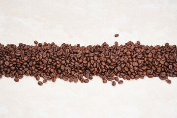 Line of a roasted coffee beans  on a beige background. 