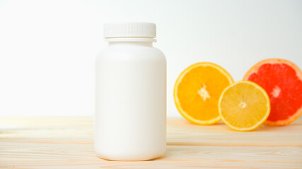 Vitamins. White empty bottle for vitamins on a background of citrus fruit slices. lemon. orange. White background. Blank Medicine bottle