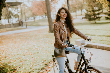 Fototapeta na wymiar Young woman riding bicycle on autumn day