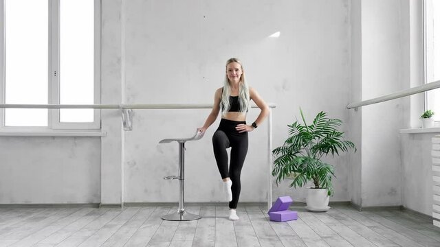 Sport and fitness. Leg exercise. Graceful female training. Young sportswoman doing morning fitness routine indoors. Blonde fit woman warming up. 4K, UHD