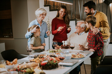 Family celebrating grandfather birthday with cake and candles at home