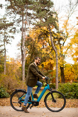 Fototapeta premium Young man with electric bicycle in the autumn park
