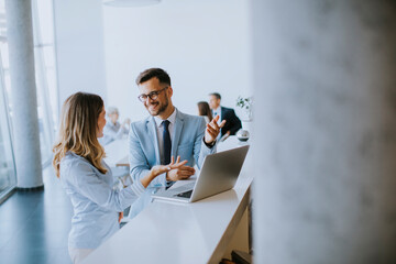 Young business couple working and discussing by laptop in the office
