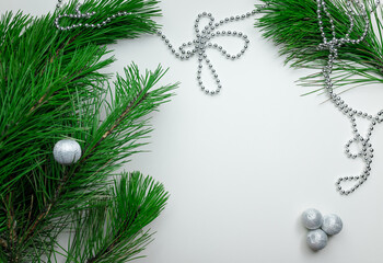 Christmas holiday background - decoration on a white table background. New year pine and silver Christmas balls. Top view. Place for text.