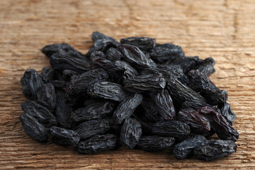 A handful of large blue raisins on a woody texture background. Selective focus.