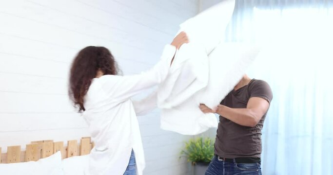 Happy family, Happy young couple playing pillow fight on the bed on weekend morning, Spending time together in family.
