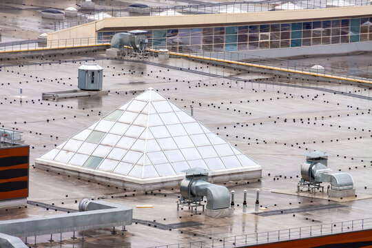 Aerial view pyramid-shaped skylight window flat roof with air conditioners top modern apartment building. Urban development and sustainable lifestyle concept. - Powered by Adobe