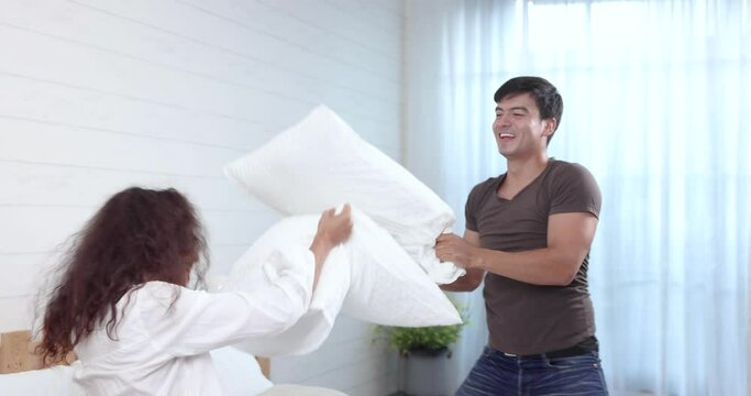 Happy family, Happy young couple playing pillow fight on the bed on weekend morning, Spending time together in family.