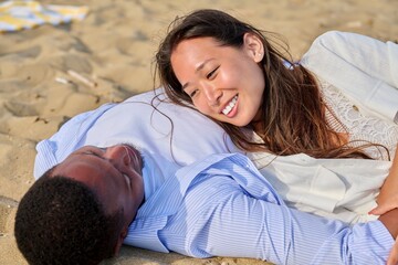 Young happy couple lying on sand, talking enjoying the senses together