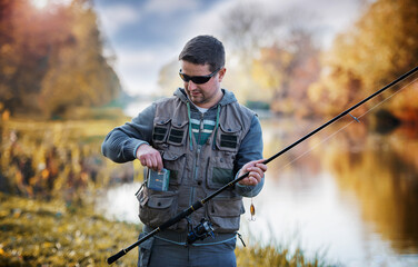 Angler choosing bait while trying to catch a trophy fish on the river. Sport and recreation concept