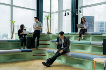 Group of young Asian business people, men and woman chilling and relaxing during break by talking...