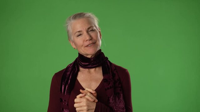 Portrait of surpised mature woman in her 50s looking at camera on green screen. Smiling elder woman posing on green screen to be keyed or composited.