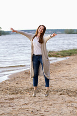 fashionable girl in trousers, blouse walks on the shore of the lake. sunset. girl jumping and having fun on the seashore