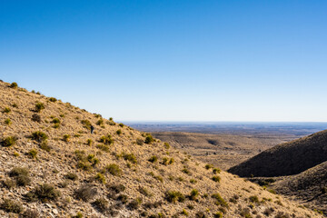 Hiker Climbs Hill With A View of West Texas In The Distance