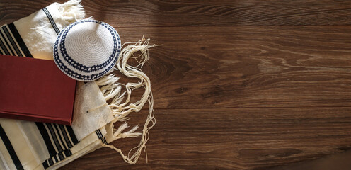 Jewish traditional prayer supplies. Talite, kippah, torah on a wooden table. Shabbatta, Bar...