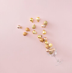 Champagne glass with golden Christmas decoration on pastel pink background. Creativ party idea. Minimal flat lay concept.