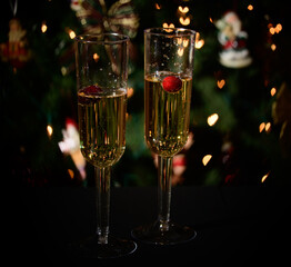 Champagne flutes with champagne and a holiday lights background.