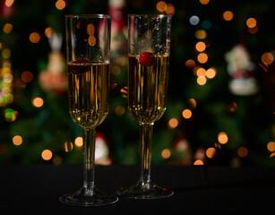 Champagne flutes with champagne and a holiday lights background.