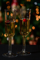 Champagne flutes with champagne and a holiday lights background.