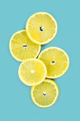 Tropical organic lemon fruit, citrus, vitamin C. Lemon slices on blue background. Creative summer minimalistic background. Flat lay, top view, copy space.