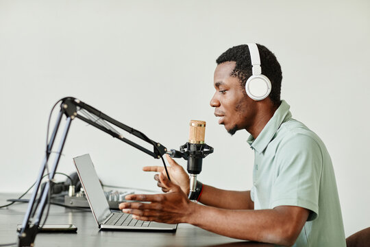Side view portrait of African-American man speaking to camera while recording podcast at home