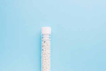 Homeopathic pills and plastic container on a blue background. Homeopathic medicine	