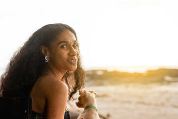 Mujer afroamericana sentada en la playa con su mascota en un hermoso atardecer