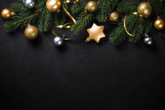 Black christmas background with fir tree and golden decorations. Flat lay image with copy space.