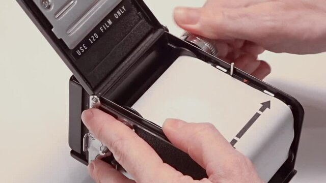 Loading film, User winding film on newly loaded medium format film camera ready to make photo