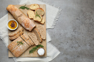 Fresh crispy ciabatta and baguette on grey table, top view. Space for text