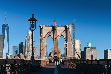 Naklejka premium New York, USA - 2021: Brooklyn Bridge, built in 1883, was the first fixed crossing of the East River. Photo taken during the day with blue sky and view to the beautiful Manhattan.