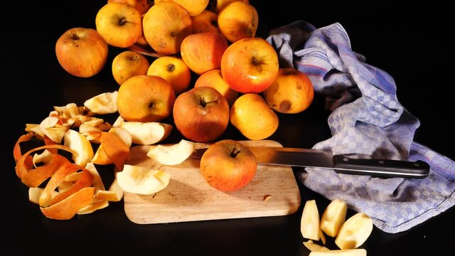 Frische orangefarbene Bio- &Auml;pfel mit Macken, B-Ware, zum Teil zerschnitten, Apfelschalen, Messer, Brettchen und blaues K&uuml;chentuch. Kamerafahrt