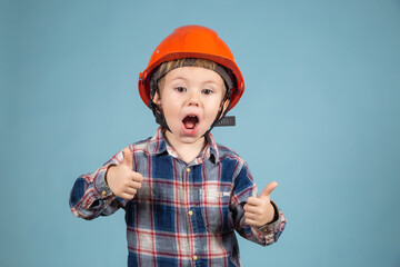 Funny boy engineer or architect in a protective orange helmet showing thumb up.