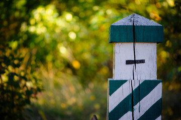 Quarterly pillar in the forest. A wooden pillar for a landmark in the forest. Forestry post. wood post with green stripes, natural background. space for text. autumn leaves in the forest