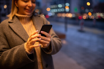 Portrait of young woman using phone while waiting the bus outdoors.