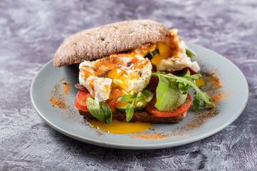 A platter of poached eggs. Poached eggs and salad on a plate. Eggs and spices. Spreading yolk from poached egg.