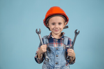 A cute girl in an orange hard hat holding wrenches in both hands.