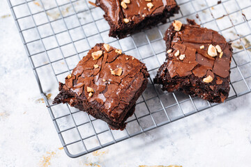 Chocolate brownies with hazelnut crumbs on top, on a tray with cacao powder, chocolate crumbs on a...