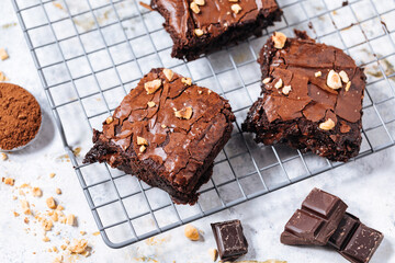 Chocolate brownies with hazelnut crumbs on top, on a tray with cacao powder, chocolate crumbs on a white rustic background. Very fudge brownies