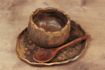 brown clay dishes on a wooden table. Soup plate, wooden spoon. Natural materials