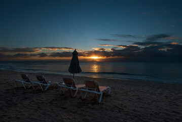 Set of chairs on a beach, on a colorful sunset as background in La Riviera Maya in Mexico.