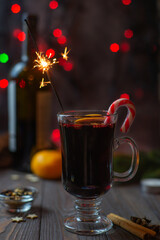 Mulled wine in a glass with sparklers and spices on a bokeh background
