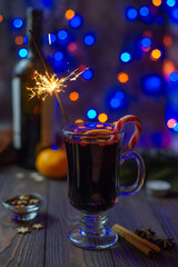 Mulled wine in a glass with sparklers and spices on a bokeh background