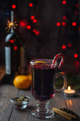 Mulled wine in a glass with sparklers and spices on a bokeh background
